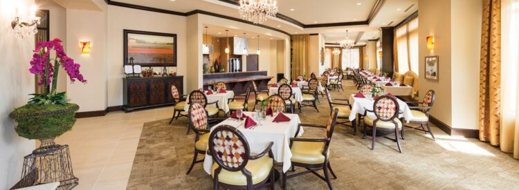upscale dining room with chandeliers and floral arangements